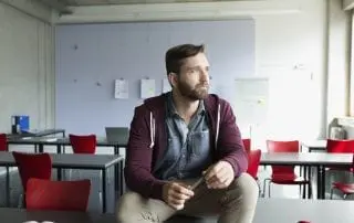 Pensive male senior student looking away in classroom